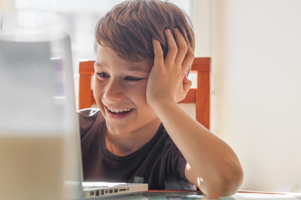 happy-child-at-computer image Girl writing on a pad in front of a laptop